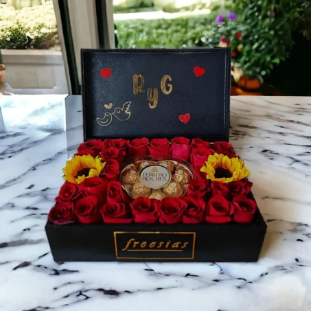 Arreglo floral de rosas rojas con chocolates Ferrero Rocher en una caja negra decorada para San Valentín.