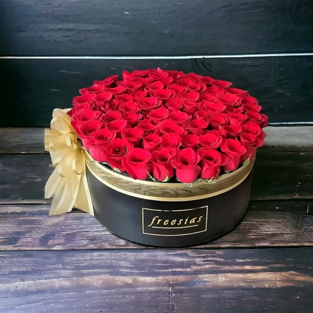 Caja redonda de rosas rojas Freesias con cinta dorada