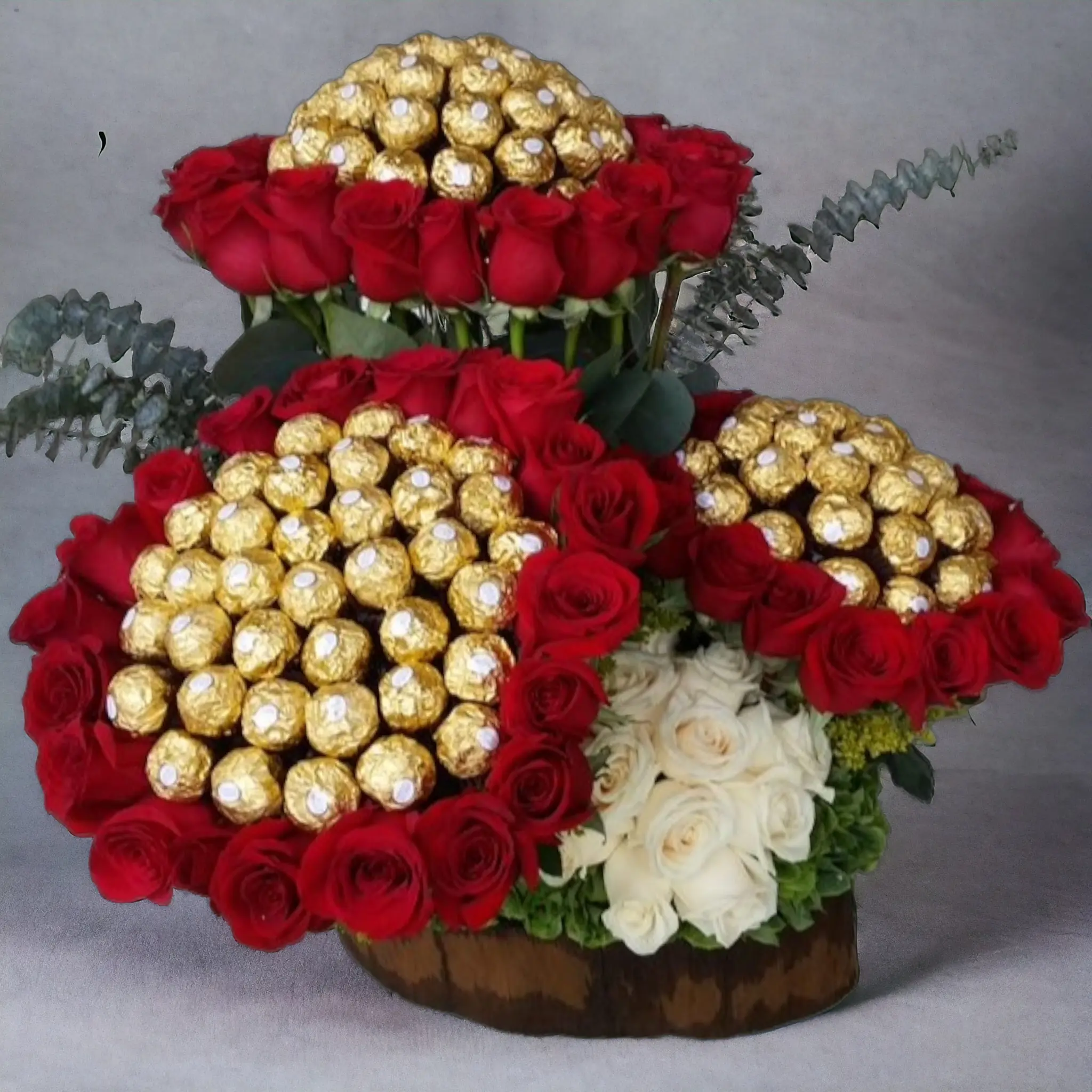 Arreglo floral con tres bouquets de rosas rojas y blancas, acompañados de chocolates